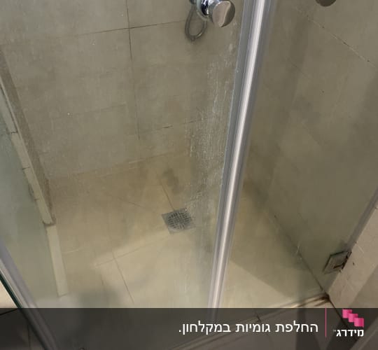 מקלחון זכוכית פינתי מותקן בחדר רחצה עם ידיות ופסי איטום